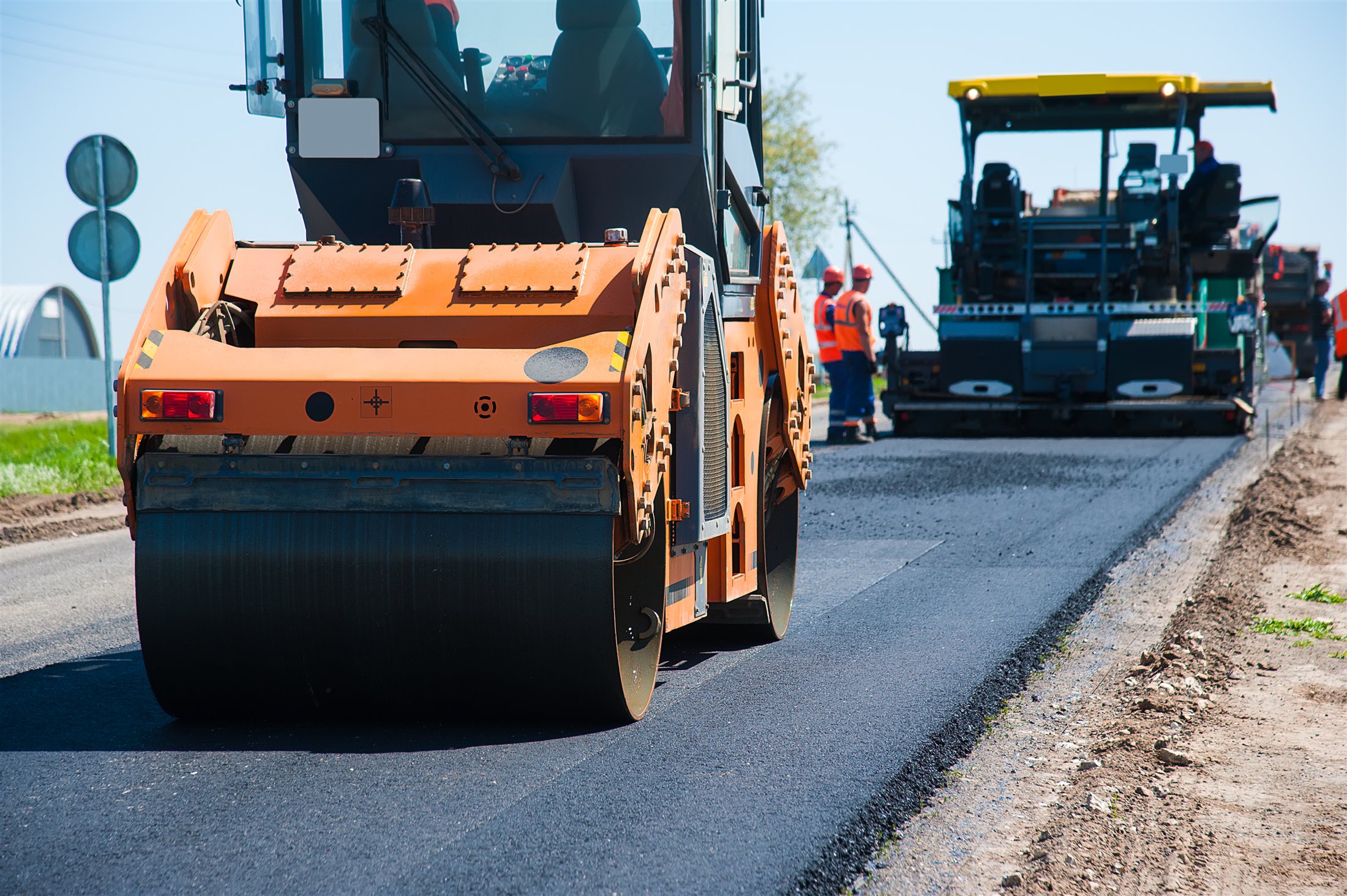 Road construction team paving fresh asphalt with heavy equipment